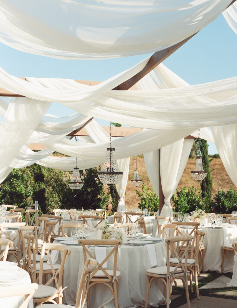 Jeune Perché wedding reception space with built-in draping, wooden tables, and crossback chairs in Fallbrook, California